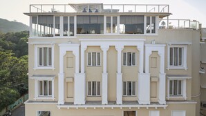 Un hôtel à plusieurs étages, doté d’une façade symétrique, de grandes fenêtres et d’un balcon situé à l’étage supérieur.