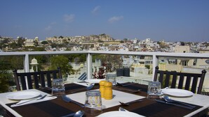 Une table à manger dressée pour quatre personnes, avec une vue sur la ville en arrière-plan.