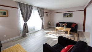 A living room with a black sofa, a wooden coffee table, and a yellow rug. - Central, 2 bedroom King/Queen, Semidetached House in French Quarter (Edmonton)