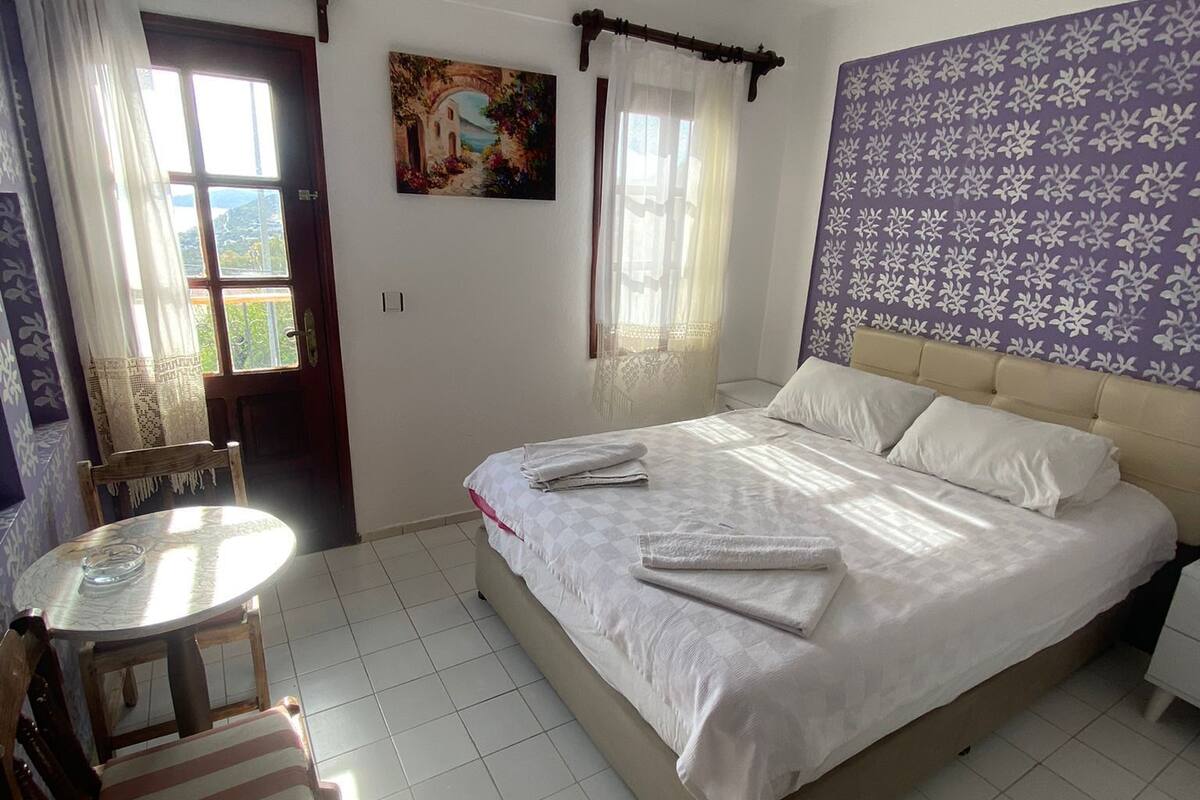 A bedroom with a bed, a round table, and a chair.