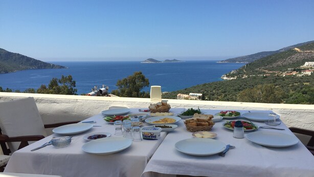 A table set for a meal with a view of the sea and hills. - Sevgi Hotel Kalkan (Kas)