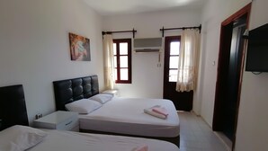 A hotel room with two beds, a flat-screen TV, an air conditioning unit, and a painting on the wall. - Sevgi Hotel Kalkan (Kas)