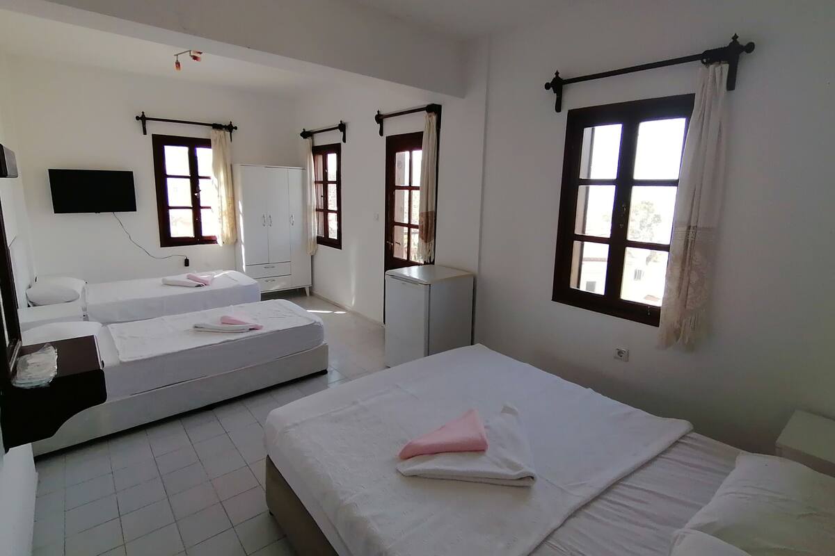 A hotel room with two beds, a TV, a wardrobe, and a window with curtains.