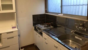 A compact kitchen with a gas stove, a sink, and a window with frosted glass. - Michio's House (Ebina)