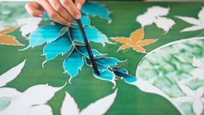A hand holding a black pen over a map with a green background and white and orange leaf patterns. - Vivo by Plush (Kuala Lumpur)