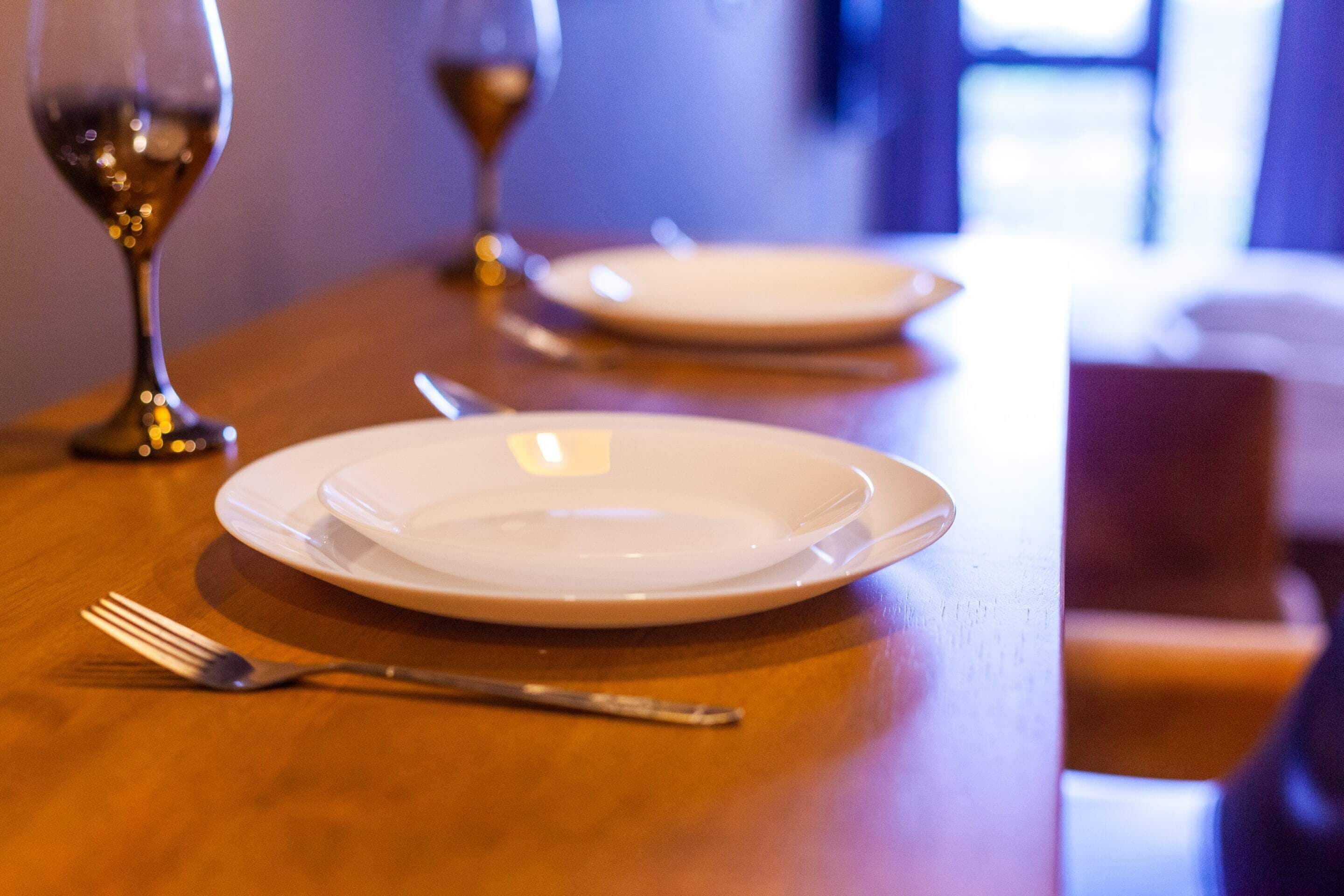 A dining table with a fork and a wine glass.