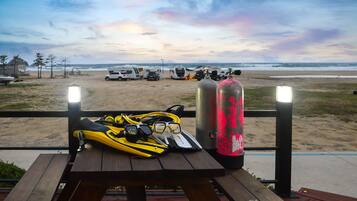 A beachside picnic table with diving gear and two oxygen tanks.