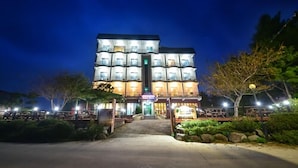 A multi-story hotel with a central entrance and a well-lit facade. - Goseong Bokee House (Goseong)