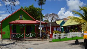Un bâtiment aux couleurs vives, avec une façade verte et un toit rouge, une clôture blanche en bois et un lampadaire.