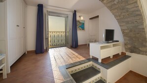 A room with a balcony, white furniture, and a television.