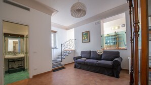A spacious living area with a staircase, a sofa, and a kitchen area visible in the background.
