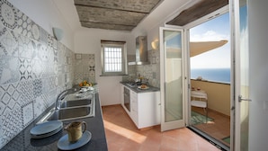 Cozinha compacta com ladrilhos estampados, forno embutido e vista para o exterior.