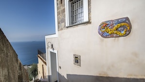 Uma rua estreita com um edifício que apresenta uma porta pequena e uma janela com grades, com vista para a costa.