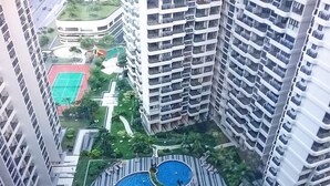 A high-rise building with multiple balconies and a central swimming pool surrounded by greenery. - Pool View Suites (Johor Bahru)