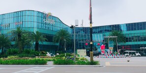 A modern building with a curved glass facade, a prominent sign reading "Greenet," and a landscaped area with palm trees and decorative sculptures. - City View Suites (Johor Bahru)