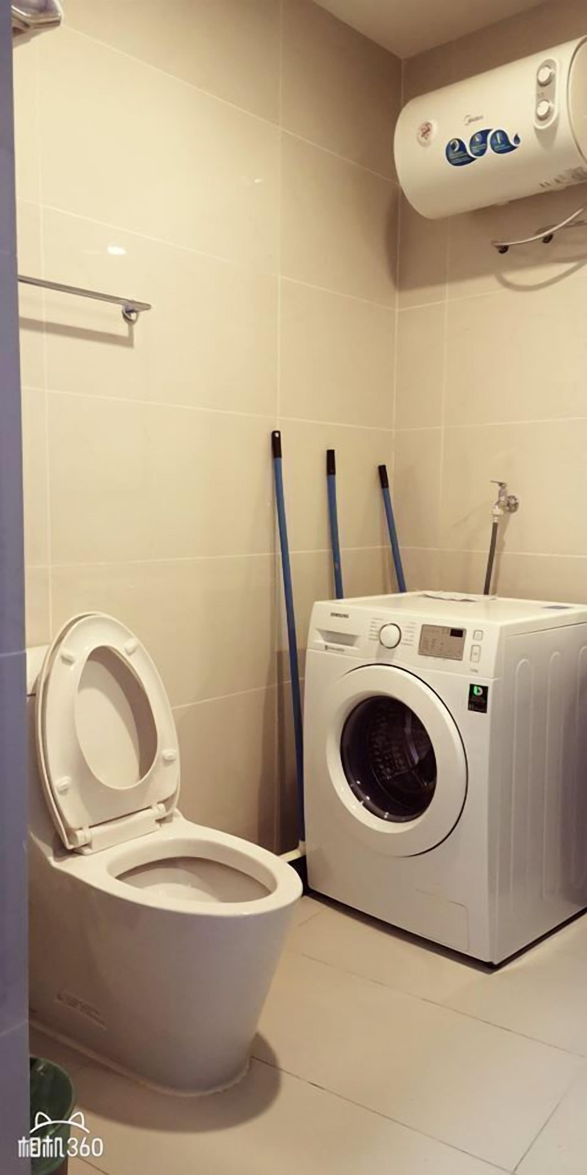 A bathroom with a toilet, a washing machine, and a hand dryer.
