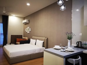 Una habitación de hotel moderna con cama, mesita de noche y una pequeña kitchenette.