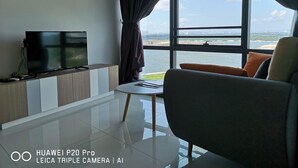 Ein modernes Wohnzimmer mit großem Fenster, Flachbildfernseher, einer Couch und einem kleinen Tisch.