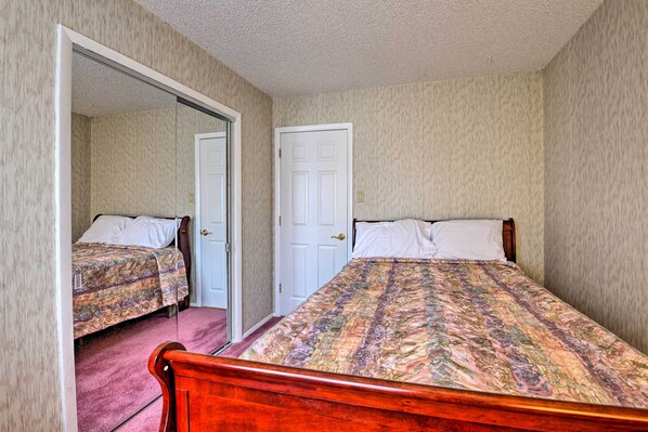A bedroom with two beds, a door, and carpeted flooring.