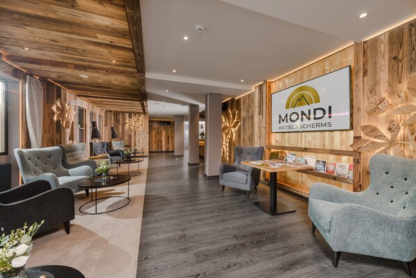 Un hall de hotel con una pared de madera, un mostrador de recepción y varias zonas de estar.