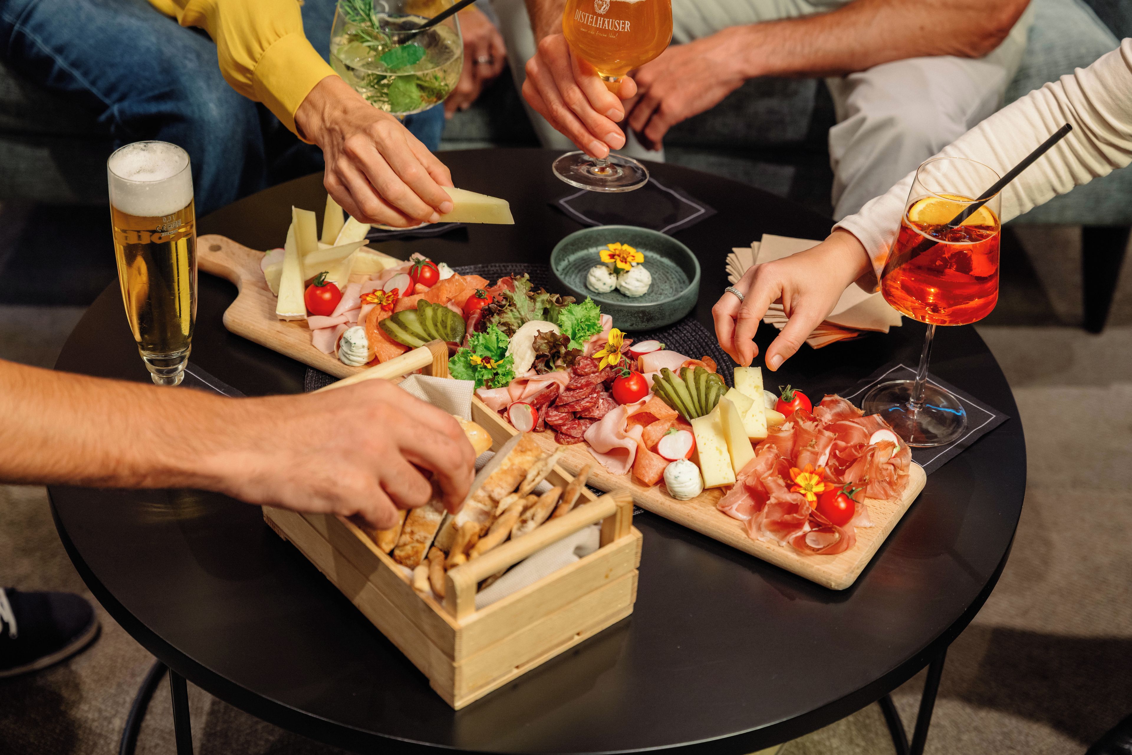 A round table with a variety of food items and drinks, including cheese, meats, and a glass of beer.