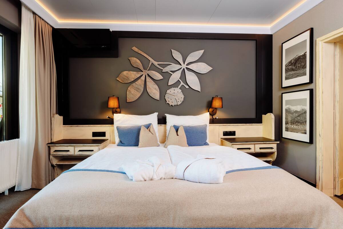 A hotel room with a large bed, two bedside tables, a wall-mounted TV, and framed pictures.