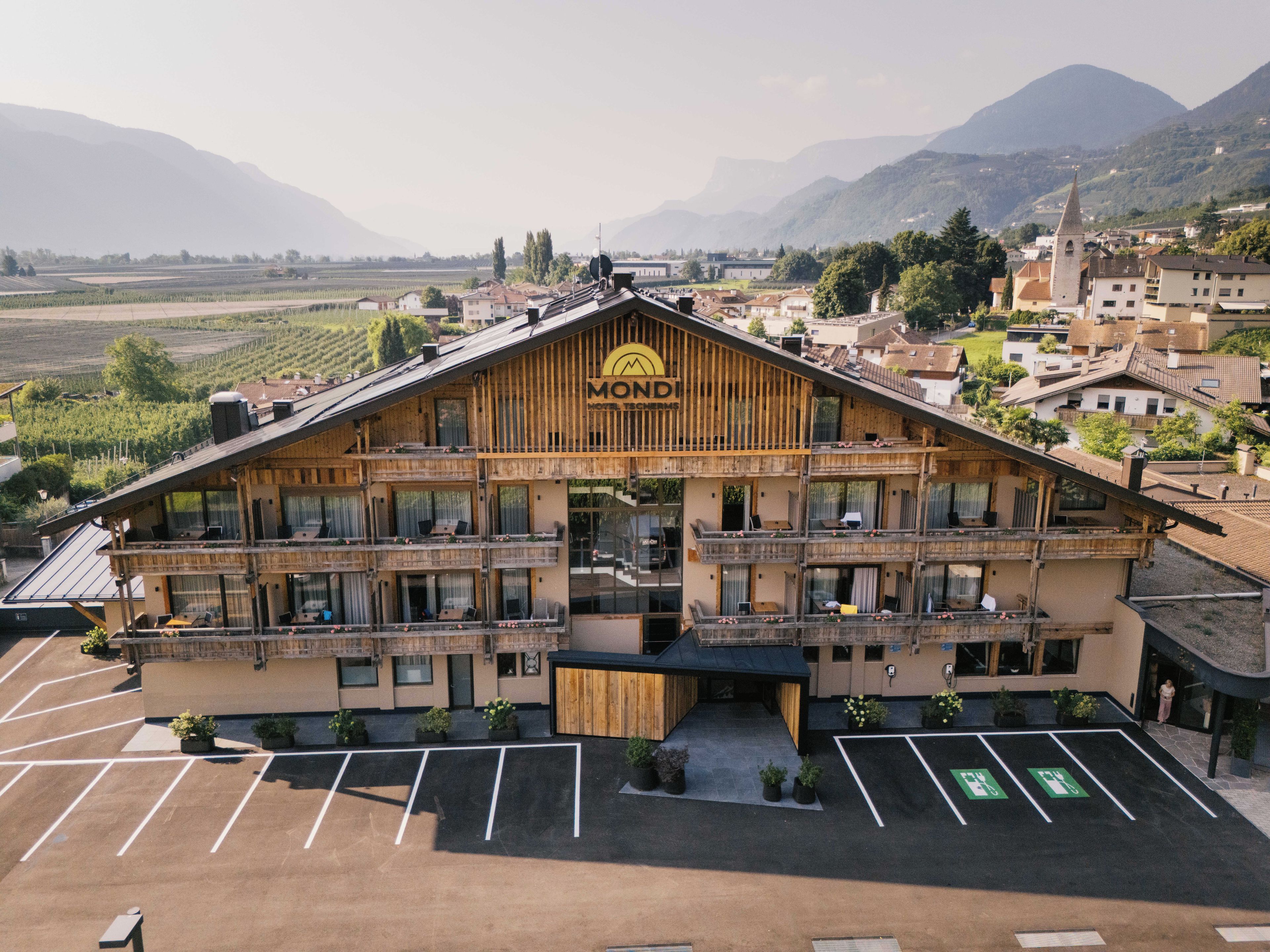Un hôtel à plusieurs étages, doté d’une façade en bois, de balcons et d’un parking.
