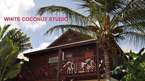 Un bâtiment en bois doté d’un balcon, entouré d’une végétation tropicale.