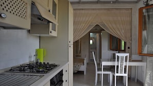 Une cuisine de taille réduite, équipée d’une cuisinière à gaz, d’une petite fenêtre et d’un coin repas avec une table et des chaises.