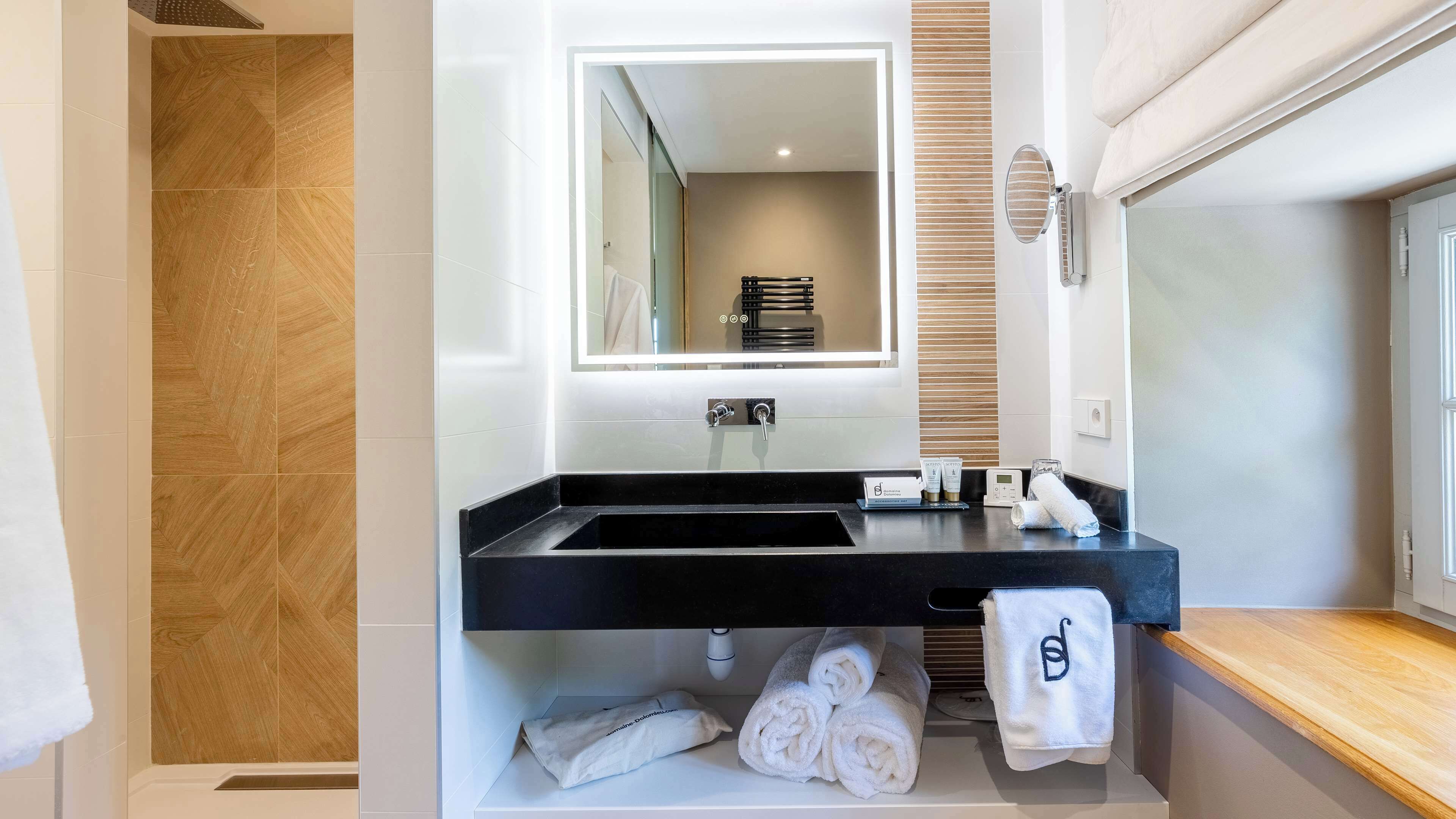 Un baño moderno con un lavabo negro, un espejo y un toallero.