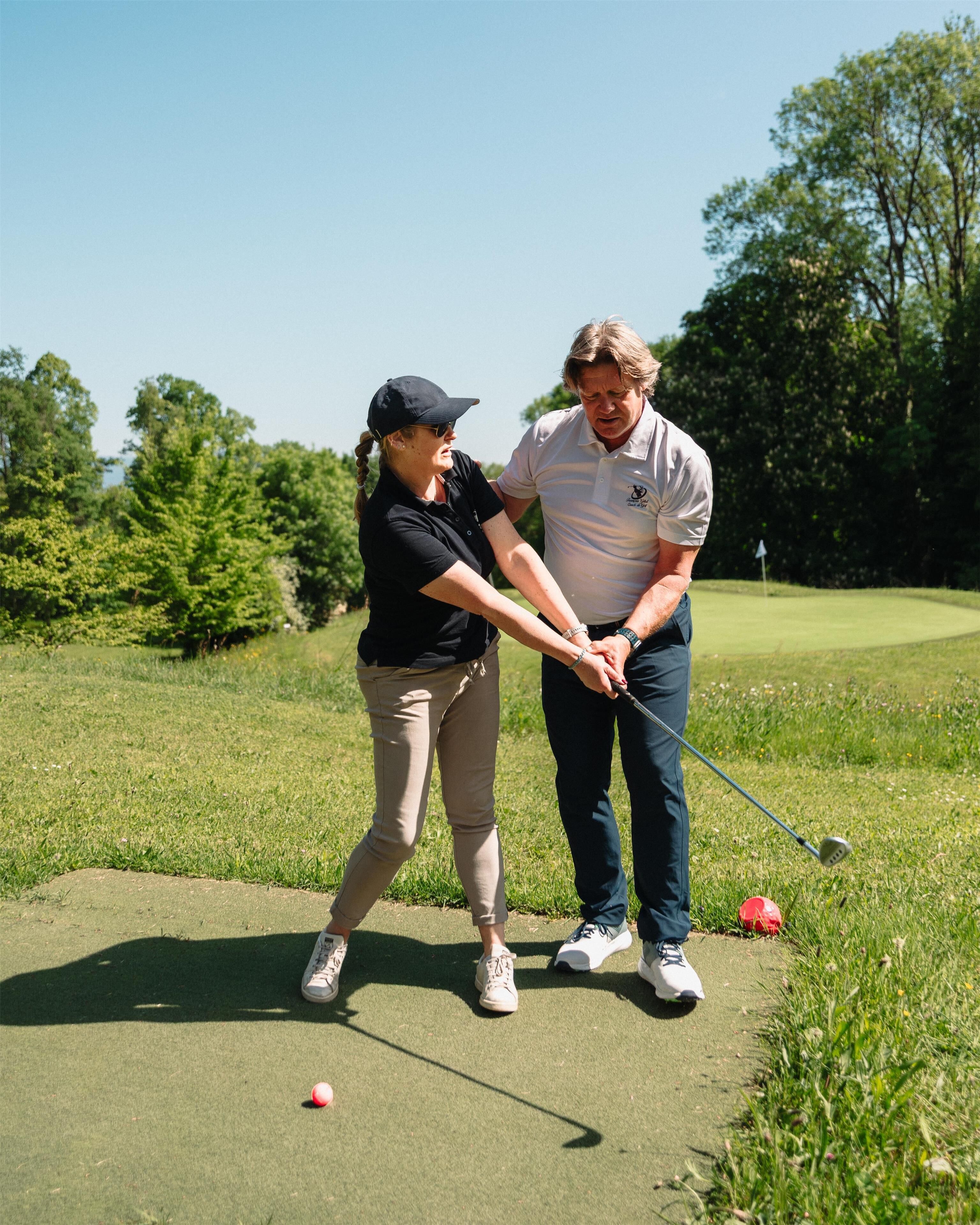 Une personne jouant au golf sur un terrain verdoyant, avec des arbres en arrière-plan.