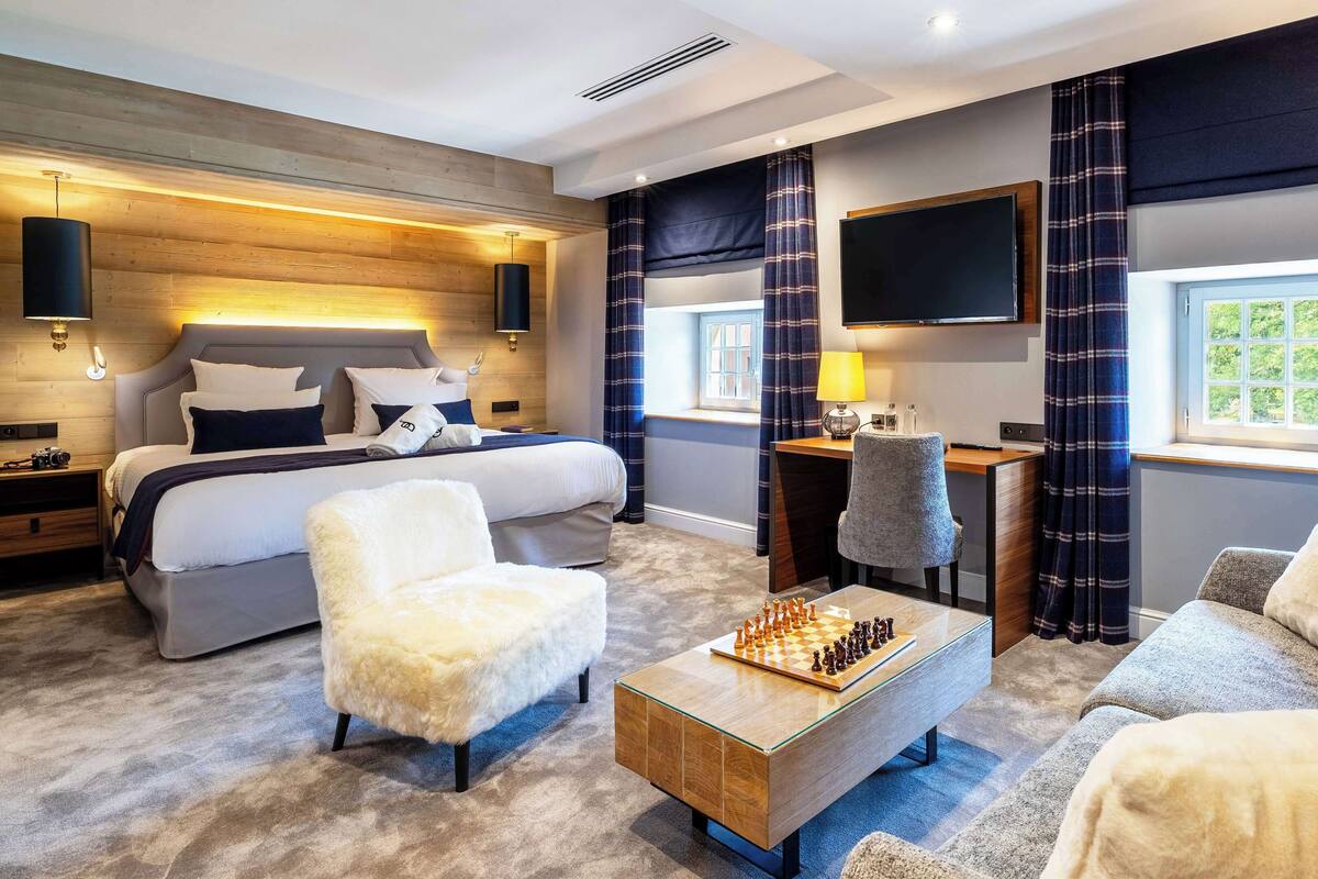 Una habitación de hotel moderna con una cama grande, un escritorio, un televisor y un tablero de ajedrez.