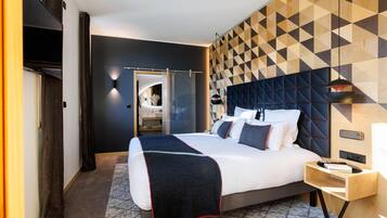 Una habitación de hotel moderna con una cama grande, una mesita de noche, un armario y una pared con estampado geométrico.