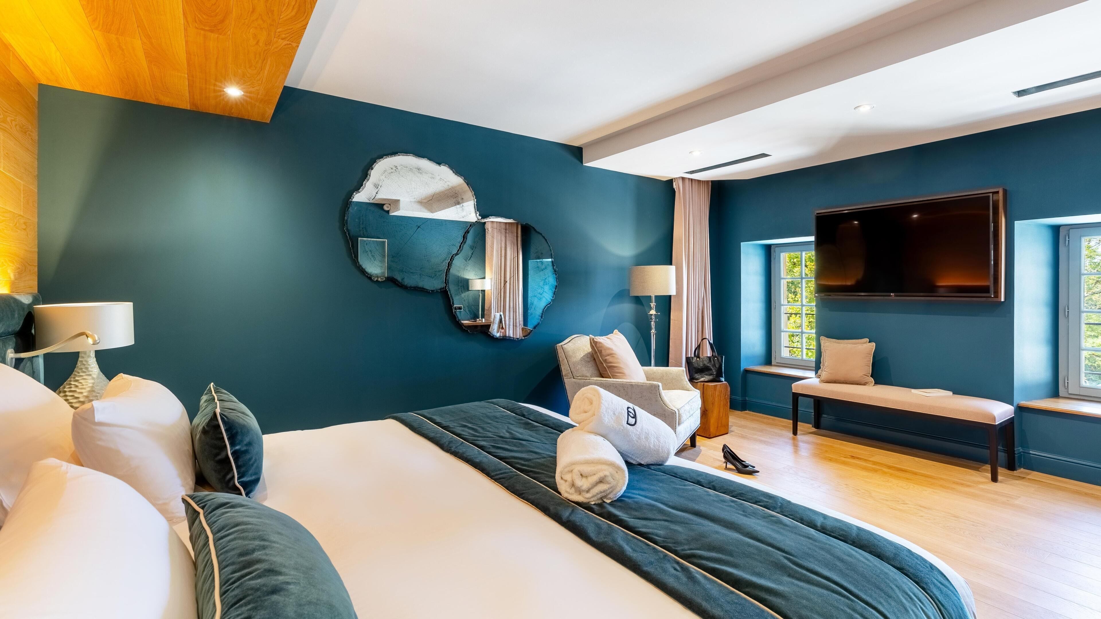A modern bedroom with a large bed, a TV, and a unique wall art piece.