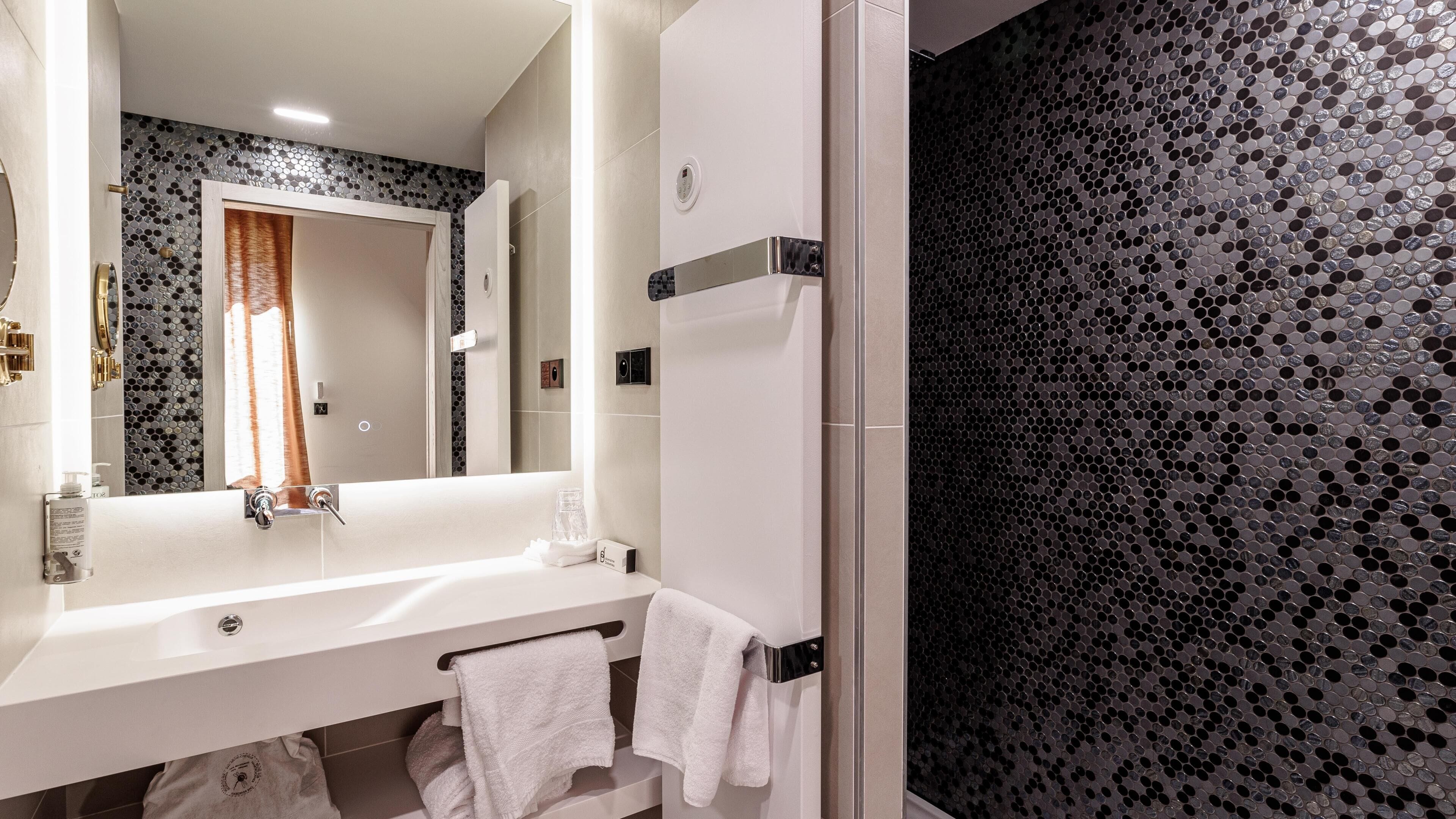 Ein modernes Badezimmer mit einem weißen Waschbecken, einem Spiegel und einer Duschkabine.