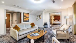 A modern living room with a sofa, armchair, and coffee table, connected to a bedroom with a bed and a bathroom. - Domaine de Dolomieu, BW Premier Collection (Dolomieu)