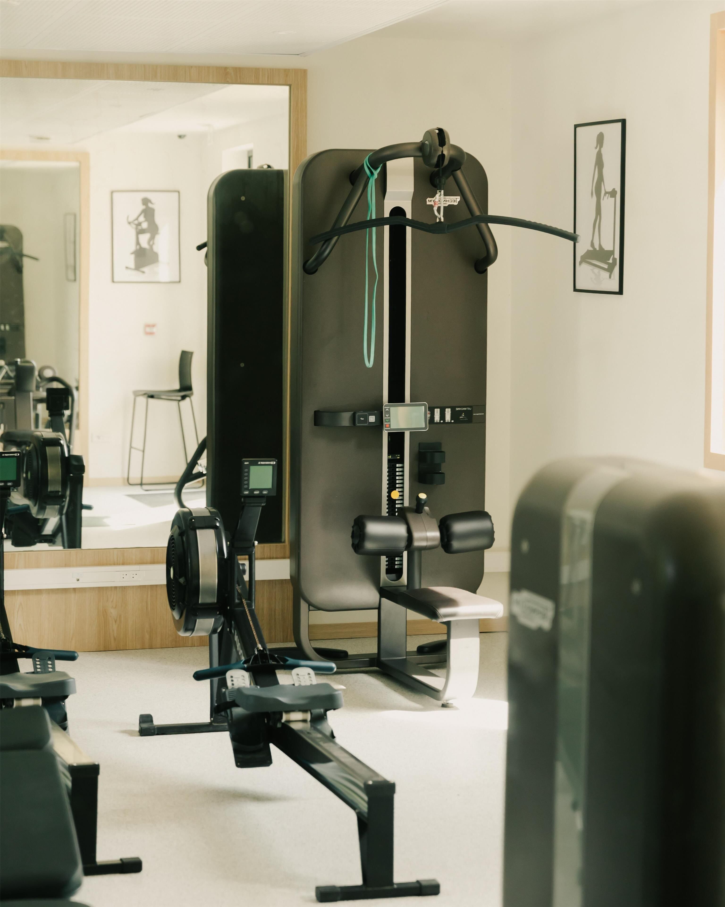 A gym with exercise equipment, a mirror, and framed artwork on the wall.