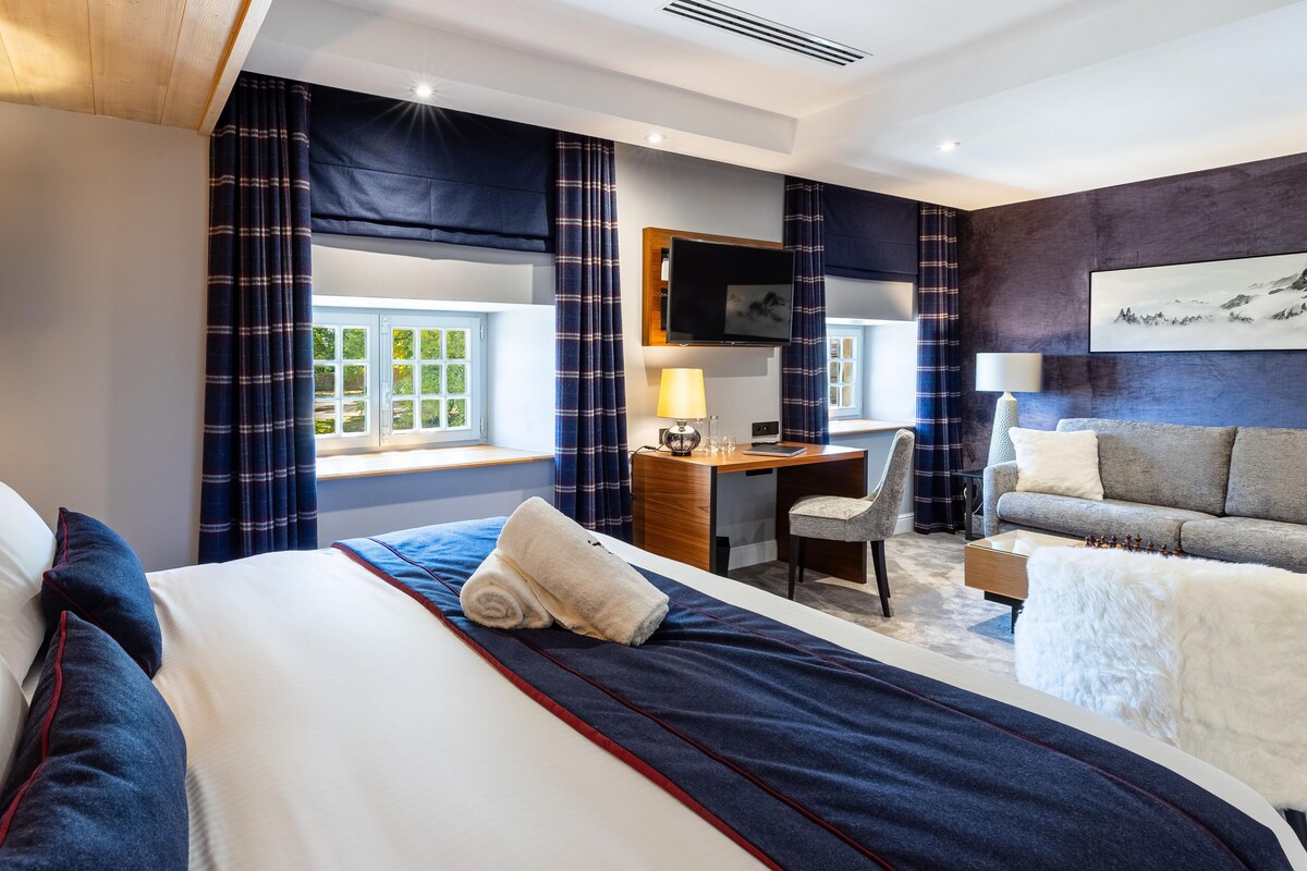 A hotel room with a bed, desk, and seating area.