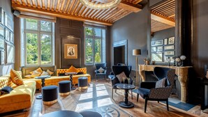 Une pièce spacieuse dotée d’une grande fenêtre, d’une cheminée et d’un coin salon avec des canapés et des fauteuils.