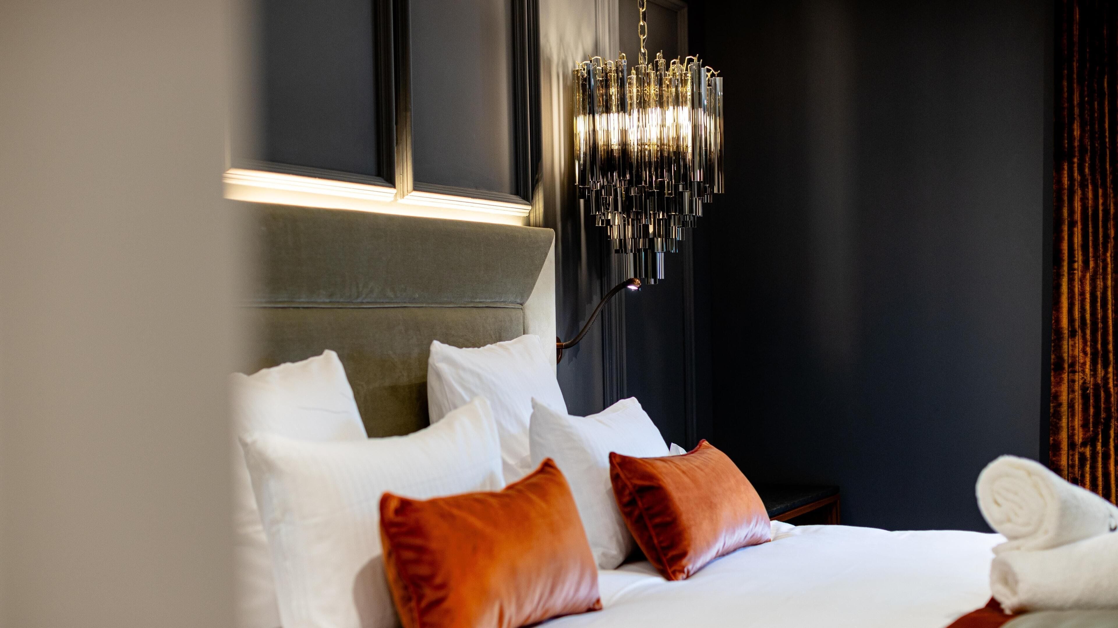 Une chambre d’hôtel avec un lit, des oreillers, une table de chevet, une lampe et une fenêtre.