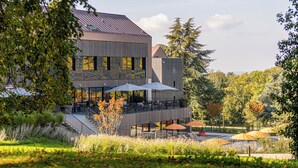 Un bâtiment moderne doté d’un espace extérieur aménagé et abrité, entouré d’arbres et d’un paysage verdoyant.