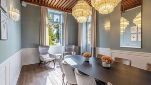 Une salle à manger avec une table en bois foncé, des chaises à revêtement blanc et un lustre.
