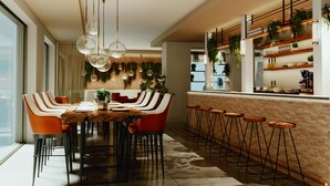 A modern dining area with a long table, multiple chairs, and hanging pendant lights.