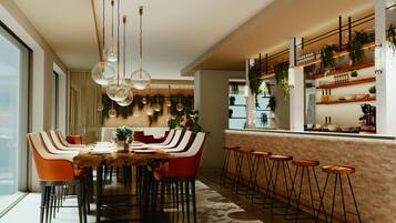 A modern dining area with a long table, multiple chairs, and hanging pendant lights.