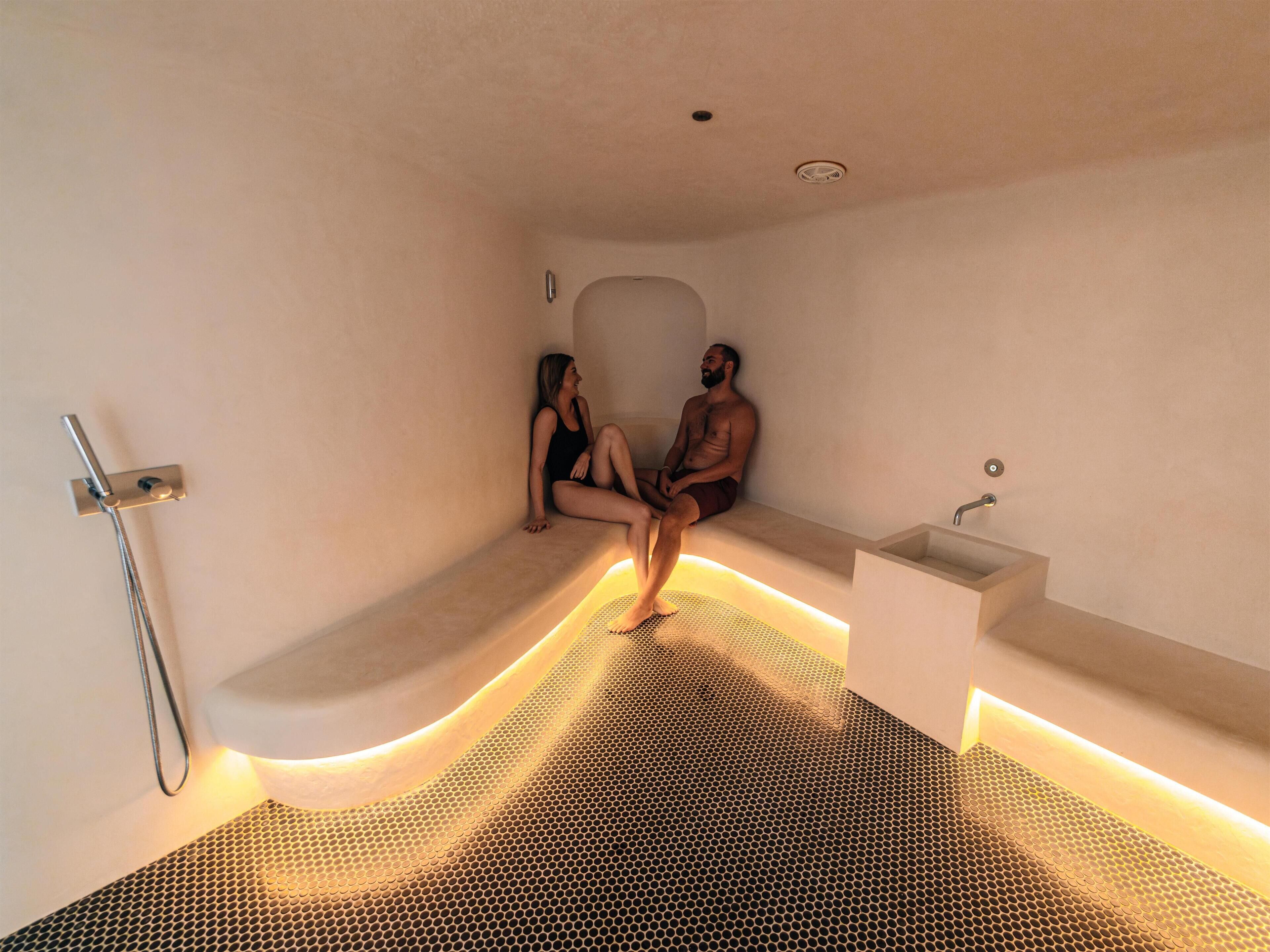 A modern bathroom with a built-in bench, a showerhead, and a sink.