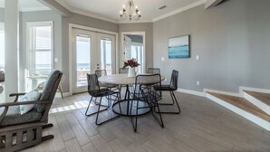 A dining area with a round table, six chairs, and a chandelier. - Beachy Keen | Late October openings. Pool, gulf front, pets (Dauphin Island)