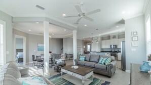 A spacious living room with a large sofa, a coffee table, and a dining area with chairs. - Beachy Keen | Late October openings. Pool, gulf front, pets (Dauphin Island)