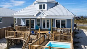 A beachfront house with a covered deck, a pool, and a large window. - Beachy Keen | Late October openings. Pool, gulf front, pets (Dauphin Island)