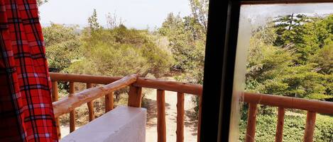 A balcony with a wooden railing, overlooking a natural landscape with various trees and shrubs.