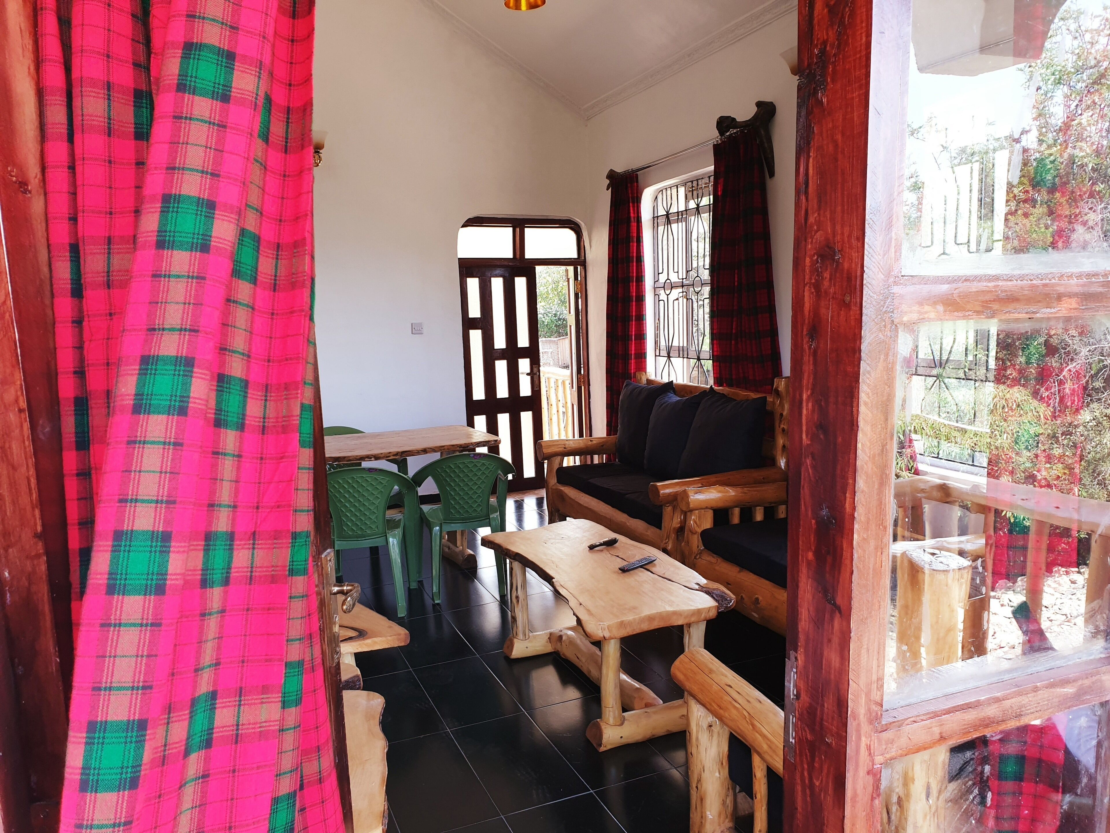A cozy room with a wooden sofa, a small table, and green chairs.
